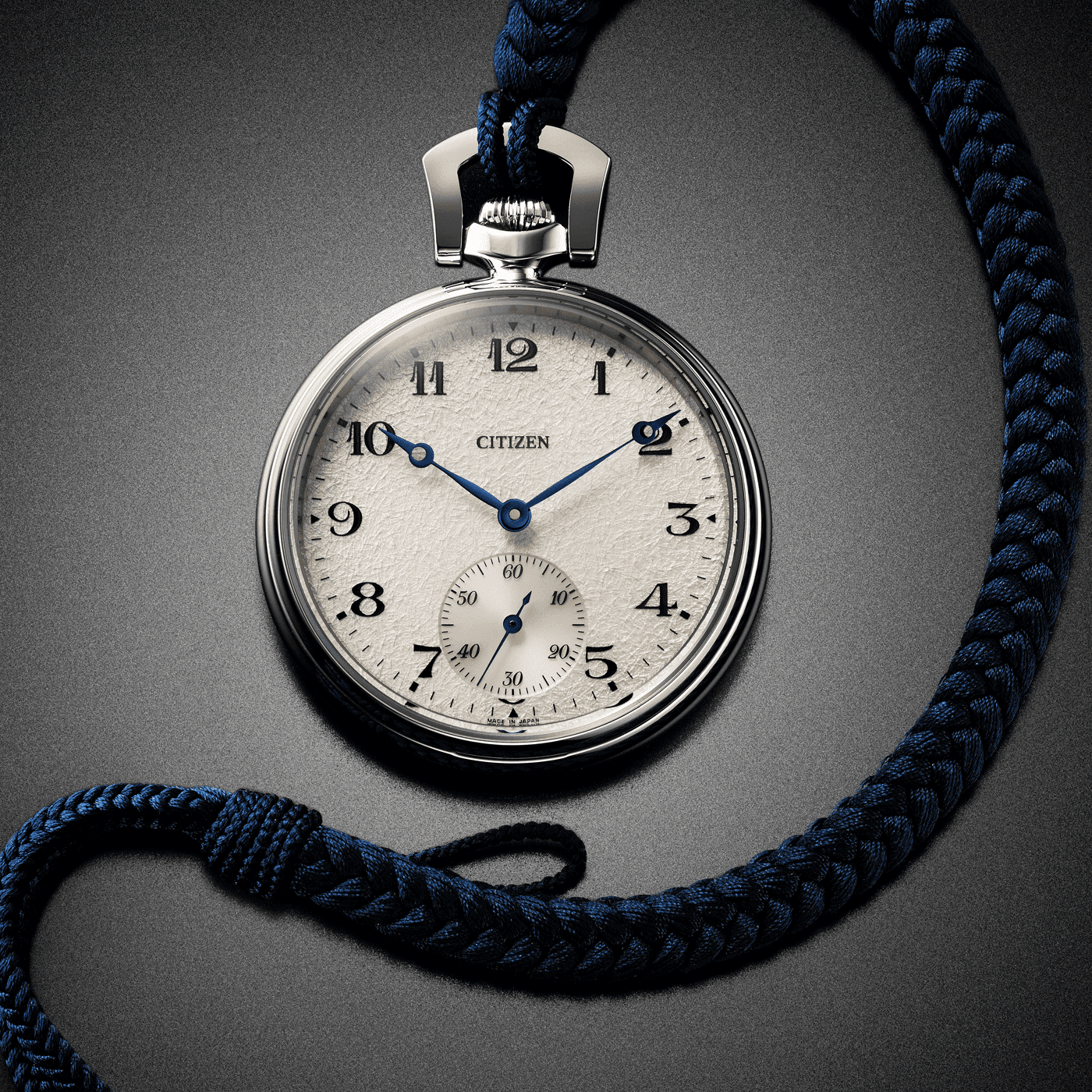 Gros plan d'une montre de poche Citizen avec un cordon tressé bleu sur fond gris.