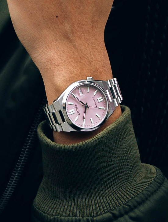 Eine Citizen Automatik-Uhr am Handgelenk, blassrosa Zifferblatt und Metallarmband.