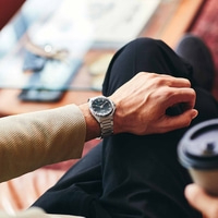 Homme portant une montre Citizen, assis avec du café, gros plan. Élégance.