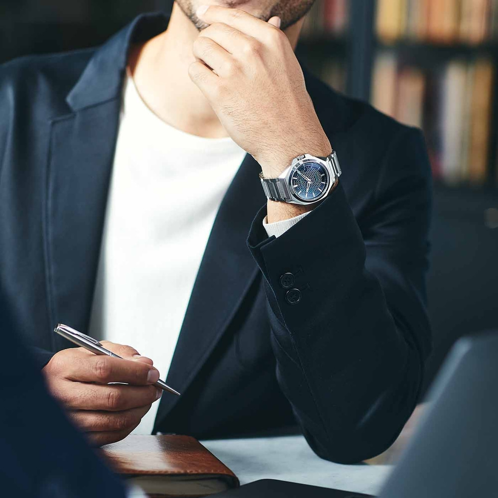 Homme en costume avec montre, tenant un stylo, réfléchissant, réunion d'affaires, bureau