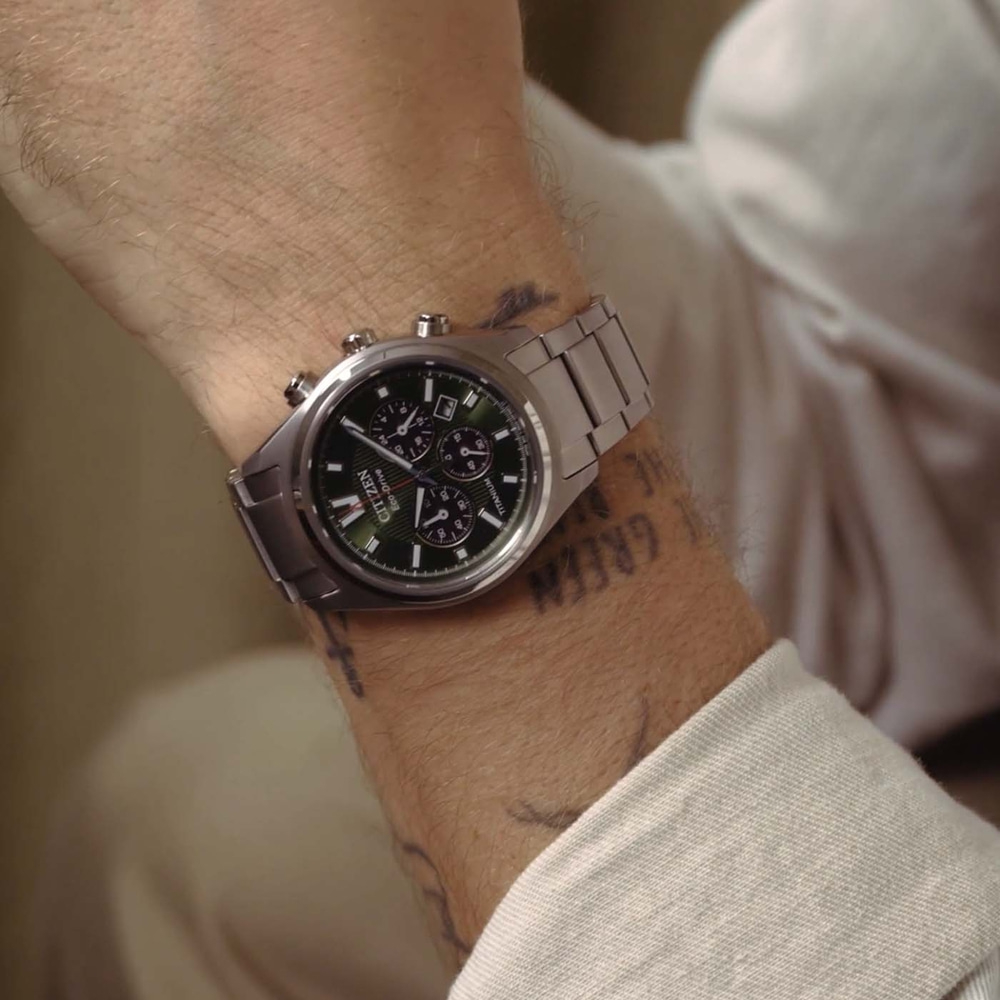 Un homme porte une montre Citizen Eco-Drive argentée avec un cadran vert.