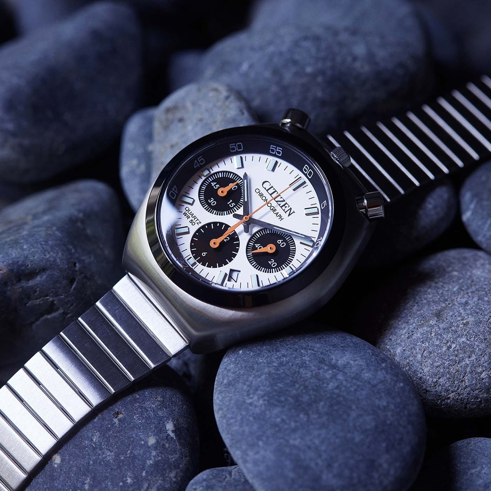 Gros plan d'une montre chronographe Citizen sur des pierres sombres.