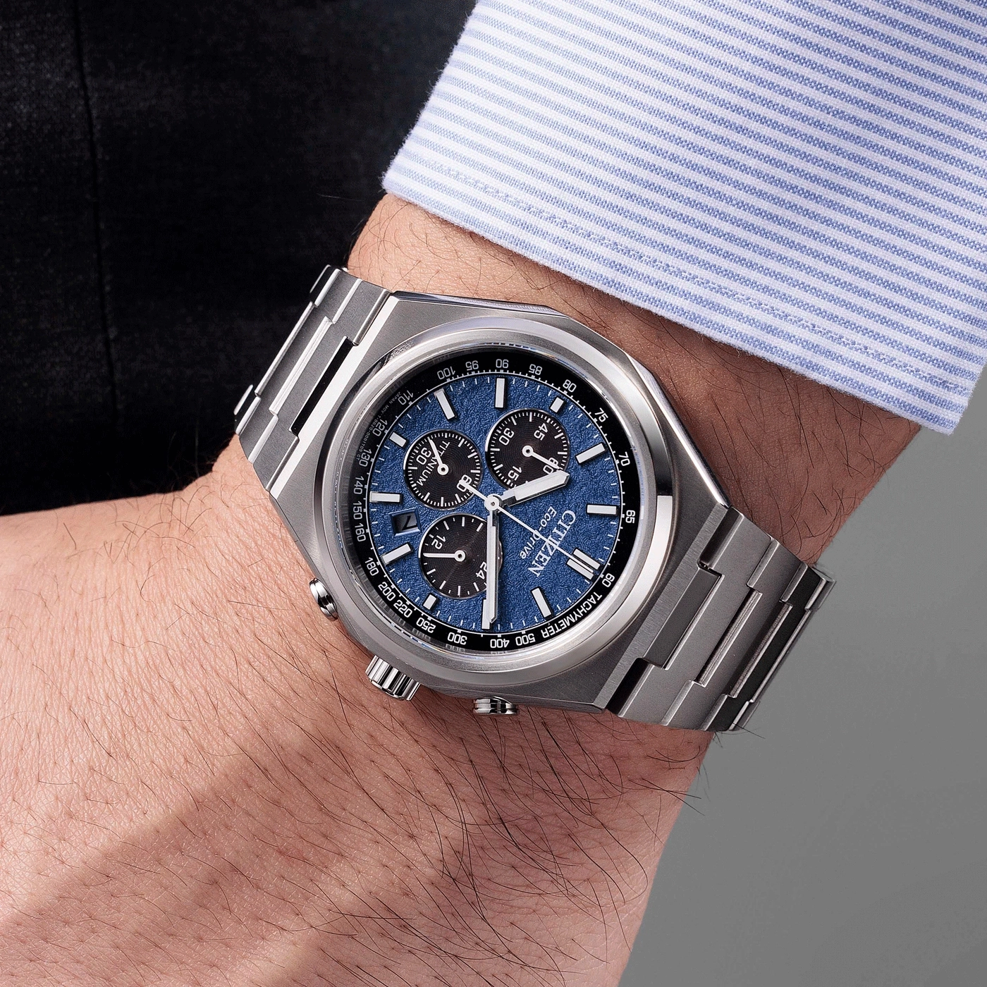 Eine silberne Citizen-Uhr mit blauem Zifferblatt, getragen am Handgelenk eines Mannes.