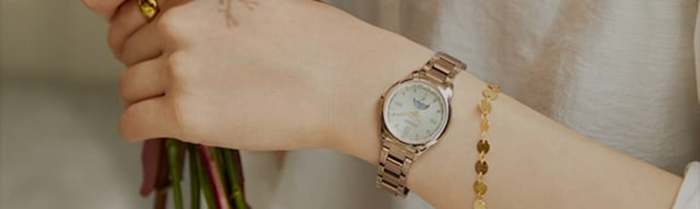 Eine Person, die eine Uhr und ein Armband trägt und Blumen hält.