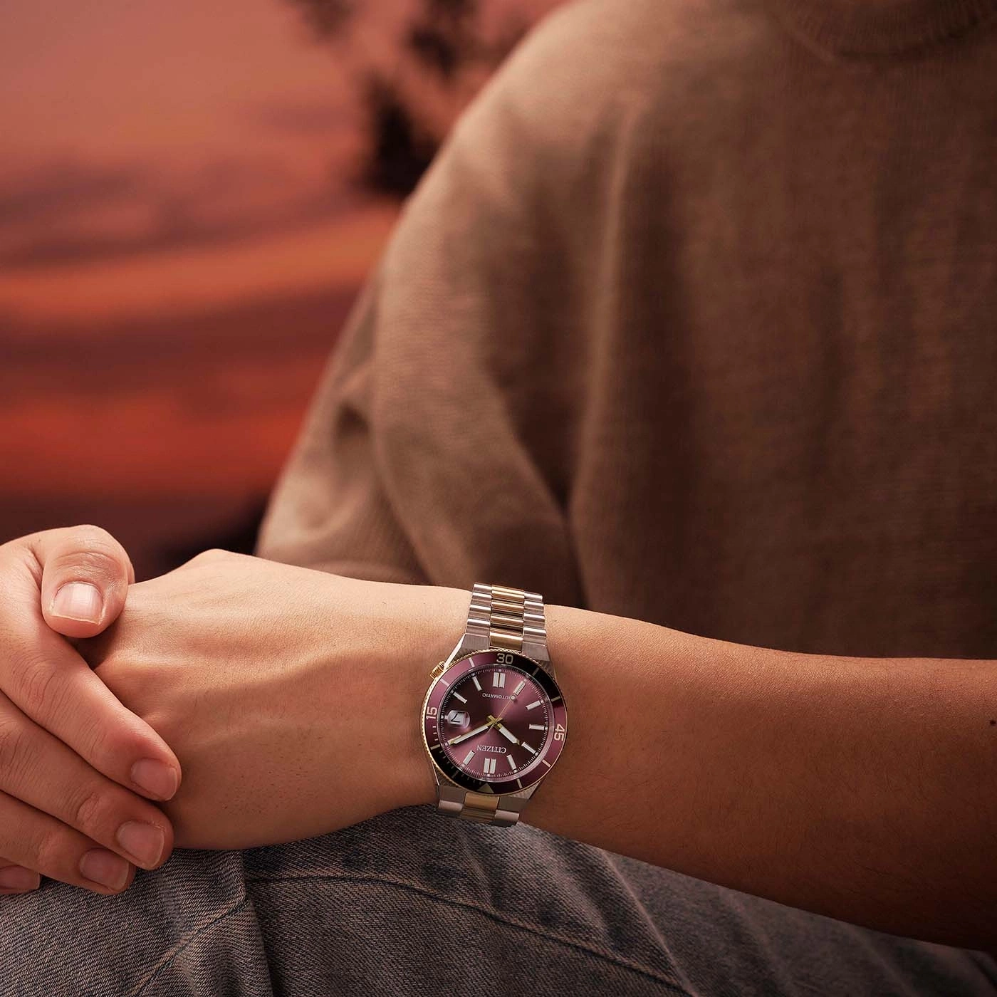Mann trägt eine zweifarbige Citizen-Uhr bei Sonnenuntergang