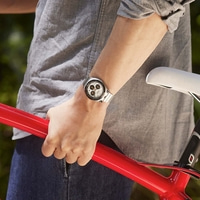 Personne en chemise grise tenant un cadre de vélo rouge, portant une montre.