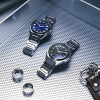 Deux montres, des bagues et un porte-clés sur une surface texturée.