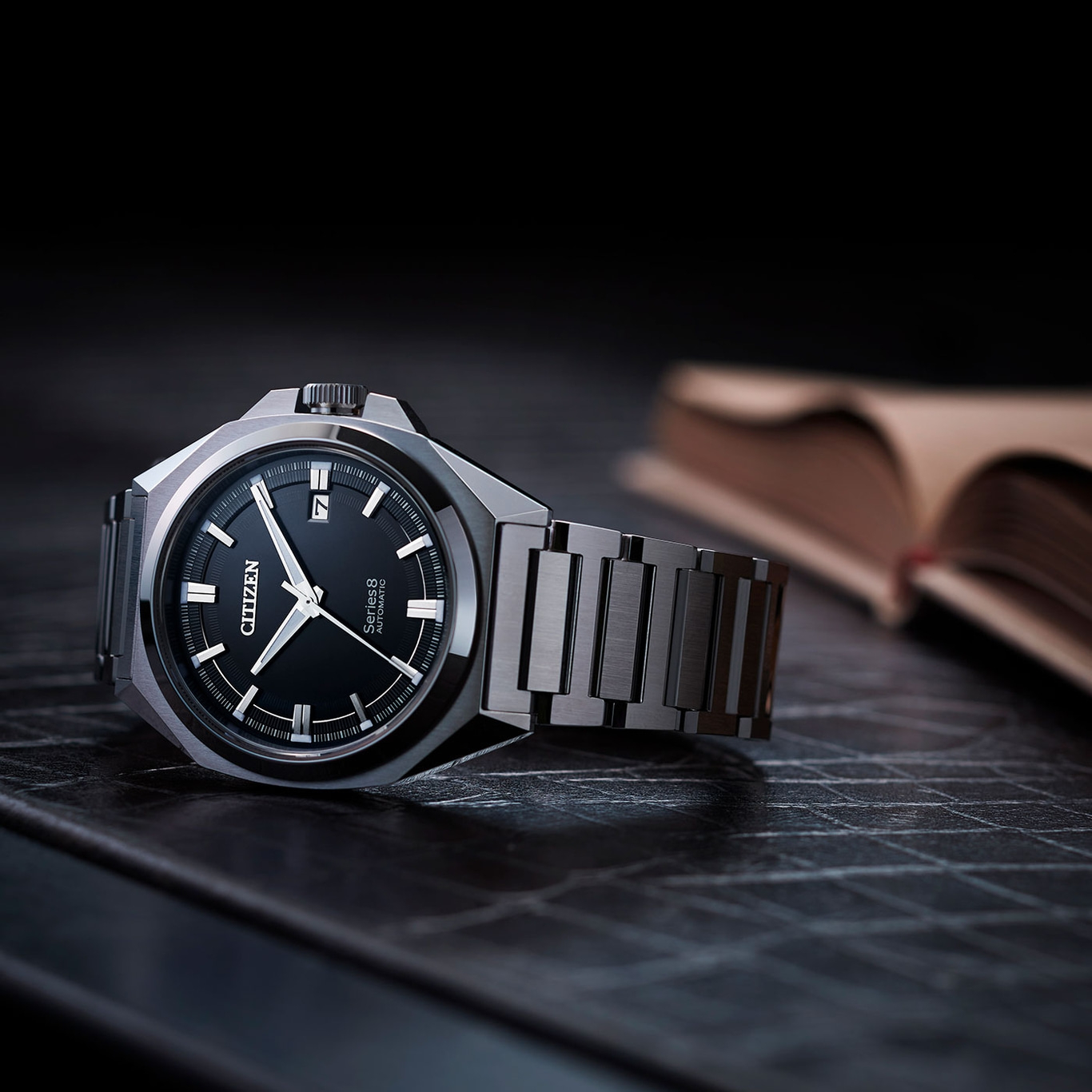 Citizen-Uhr mit schwarzem Zifferblatt und Metallband auf dunkler Oberfläche.