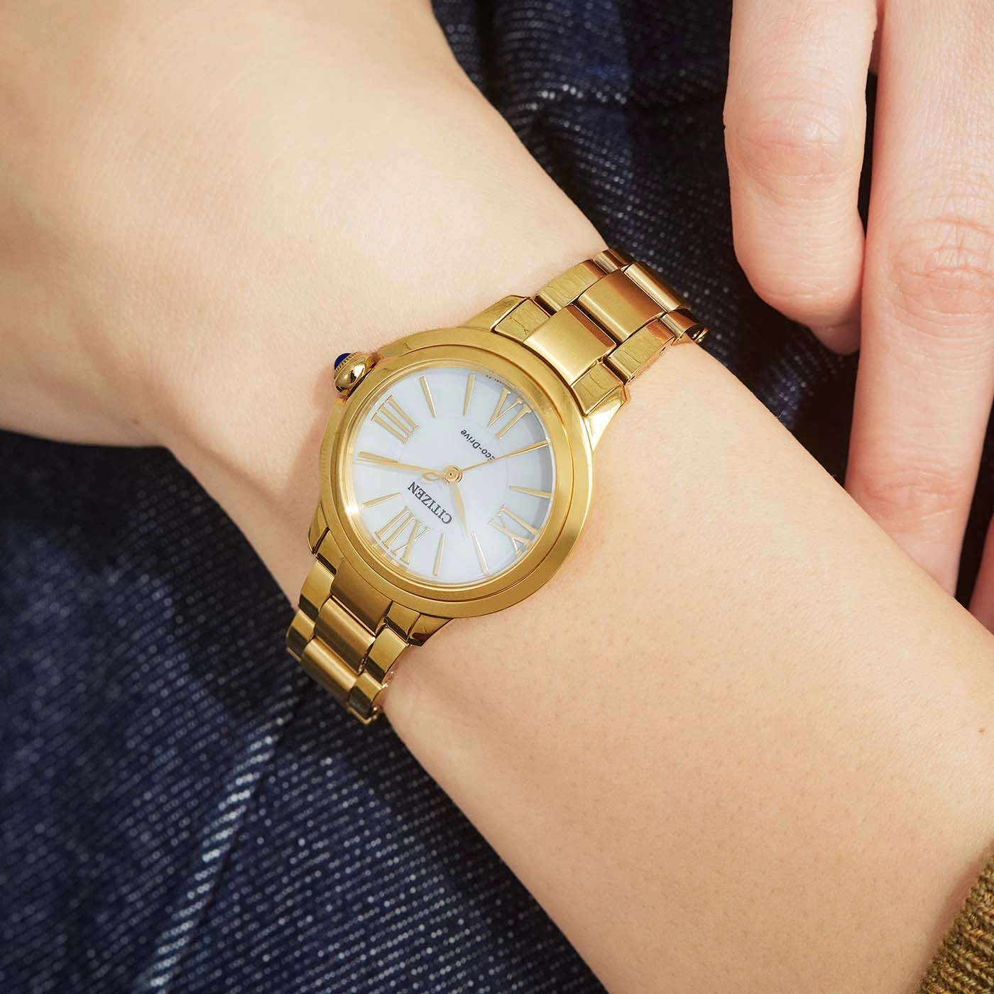 Une femme porte une montre Citizen dorée au poignet.