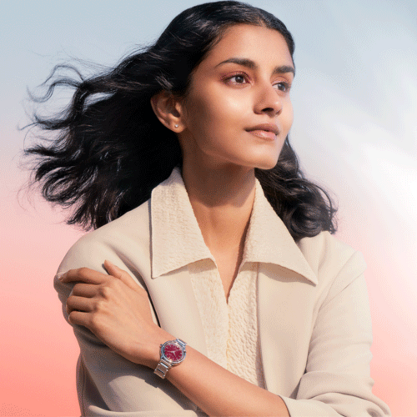 Femme portant une montre, regardant au loin, fond clair, veste, élégance.