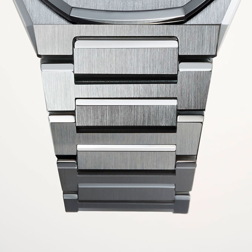 Nahaufnahme eines metallischen Uhrenarmbands mit gebürsteter Metalloberfläche und weißen Akzenten.