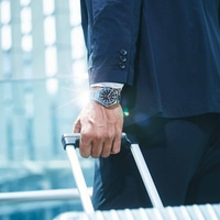 Homme en costume avec montre tenant des bagages, concept de voyage d'affaires.