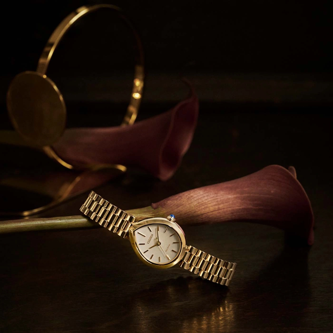Goldene Armbanduhr mit Calla-Lilien und einem goldenen Armreif.