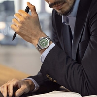Mann im Anzug mit Uhr und Stift am Schreibtisch
