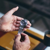 Gros plan d'une personne tenant une montre Citizen avec un cadran noir.