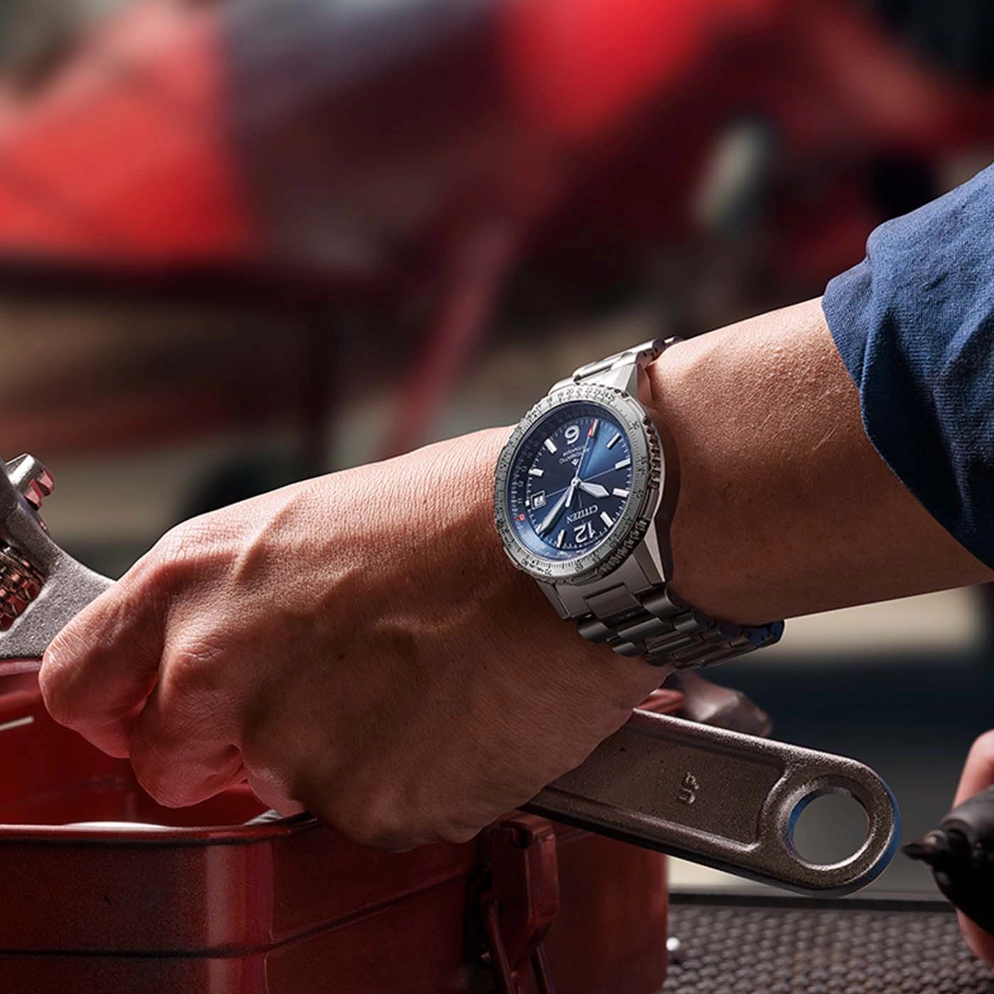 Une montre Citizen sur le poignet d'un mécanicien tenant une clé