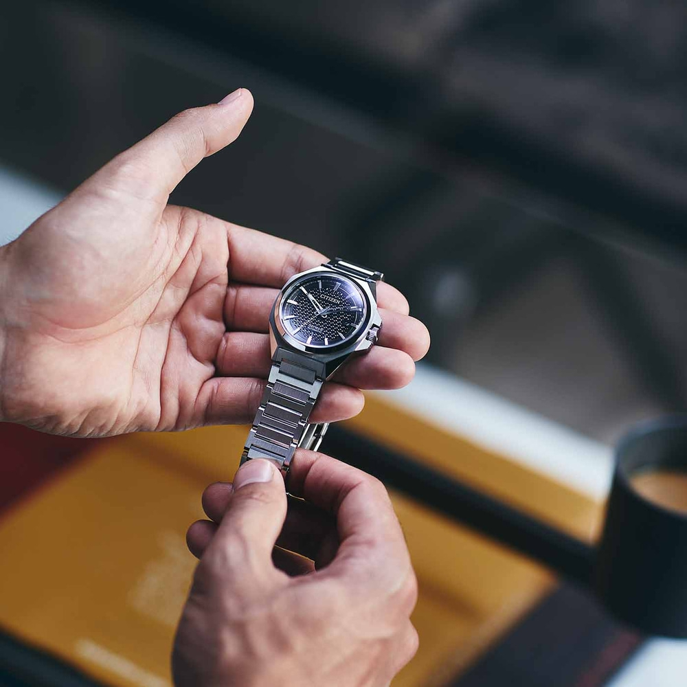 Gros plan d'une personne tenant une montre Citizen avec un cadran noir.