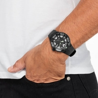 Ein Mann trägt eine schwarze Citizen-Uhr am Handgelenk, während er seine Hand in die Tasche steckt.