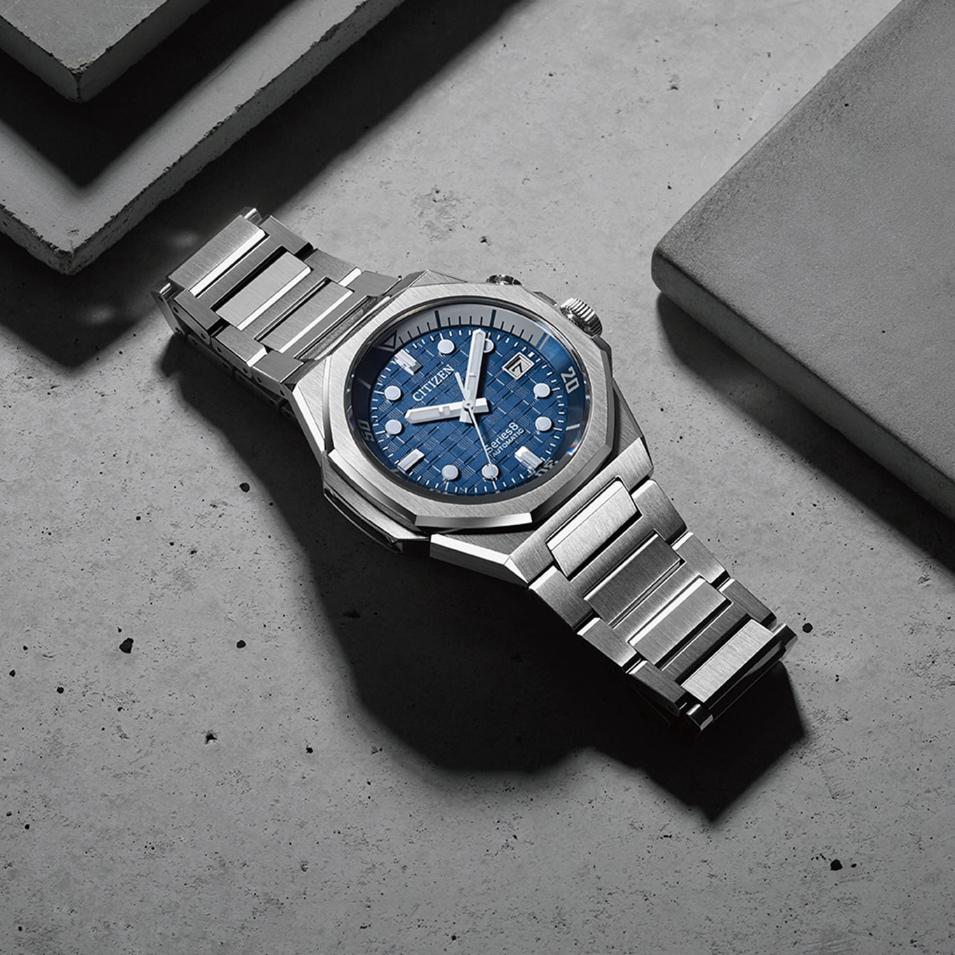 Citizen-Uhr mit blauem Zifferblatt und silbernem Armband auf Betonoberfläche