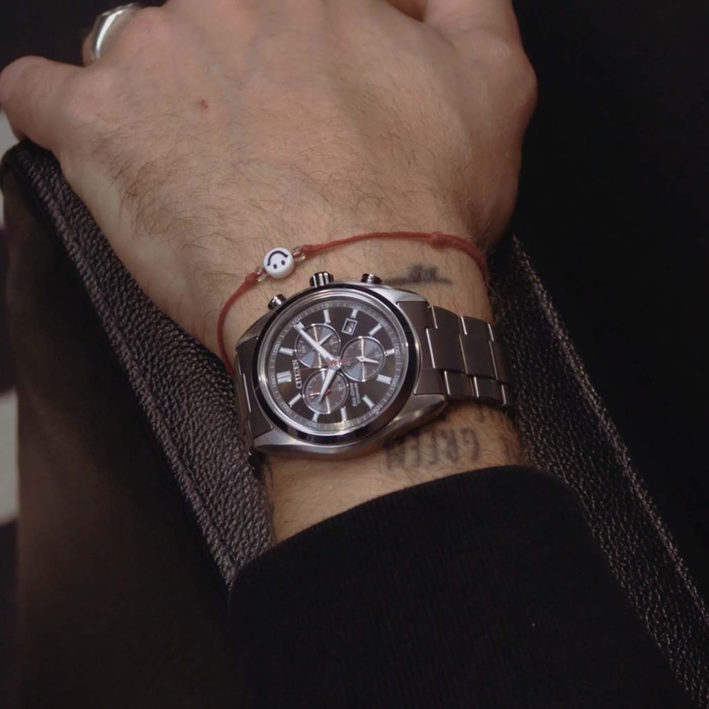 Poignet d'homme avec une montre et un bracelet smiley.