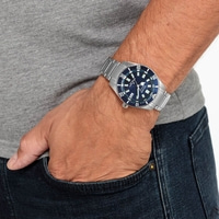 Mann trägt eine silberne Armbanduhr mit blauem Zifferblatt am Handgelenk.