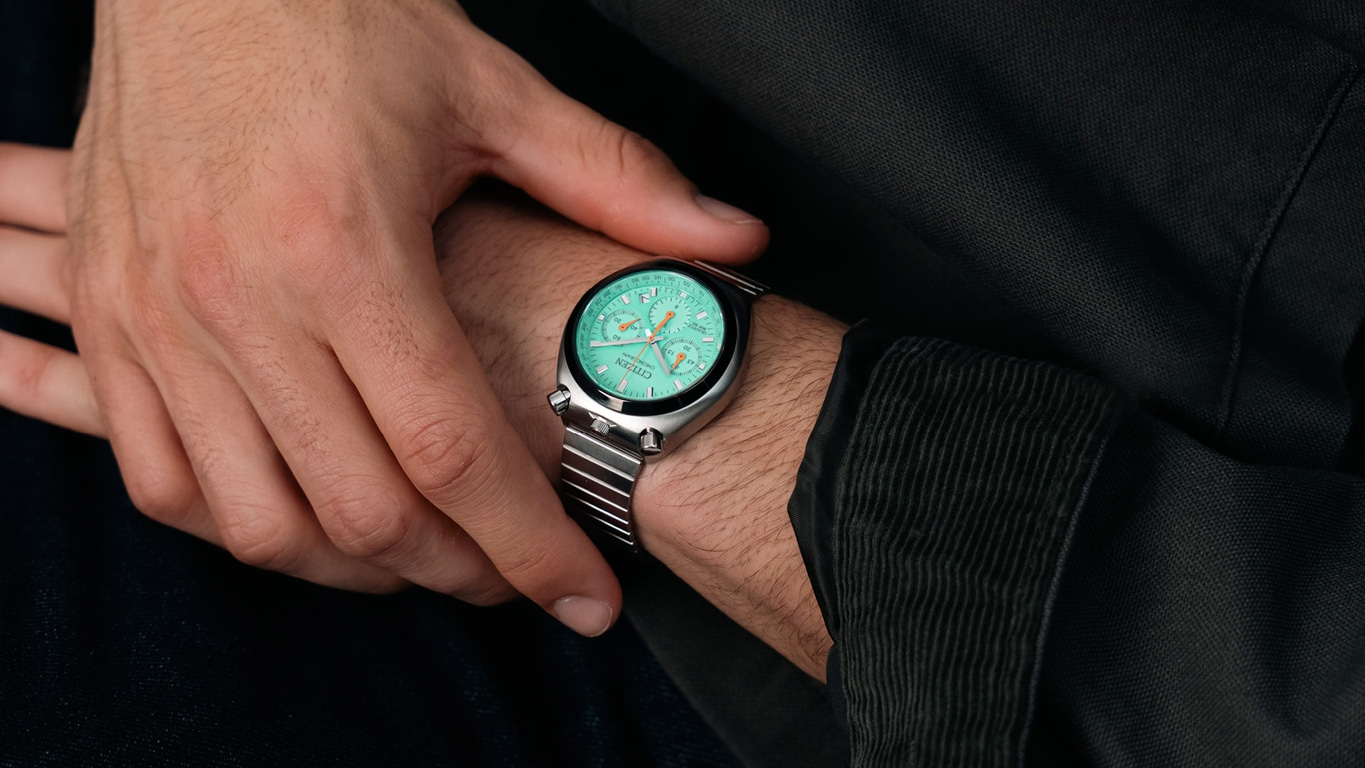 Ein Mann trägt eine grüne Citizen-Uhr am Handgelenk mit einem Metallarmband.