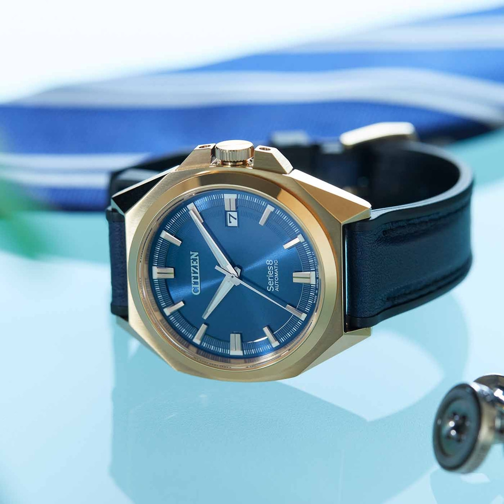 Montre Citizen avec cadran bleu et boîtier doré sur une surface bleue.