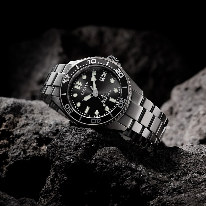 Eine Citizen-Uhr auf einem Felsen. Schwarzes Zifferblatt und silbernes Armband.