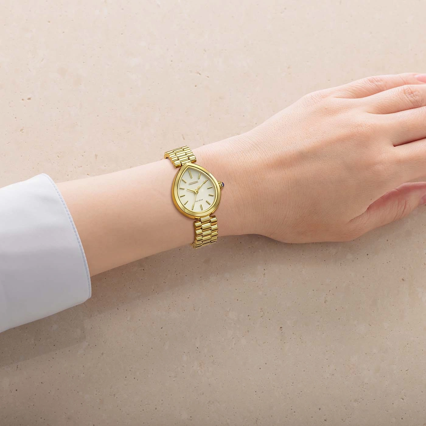 Eine Hand mit einer eleganten goldenen Armbanduhr auf hellem, strukturiertem Hintergrund.