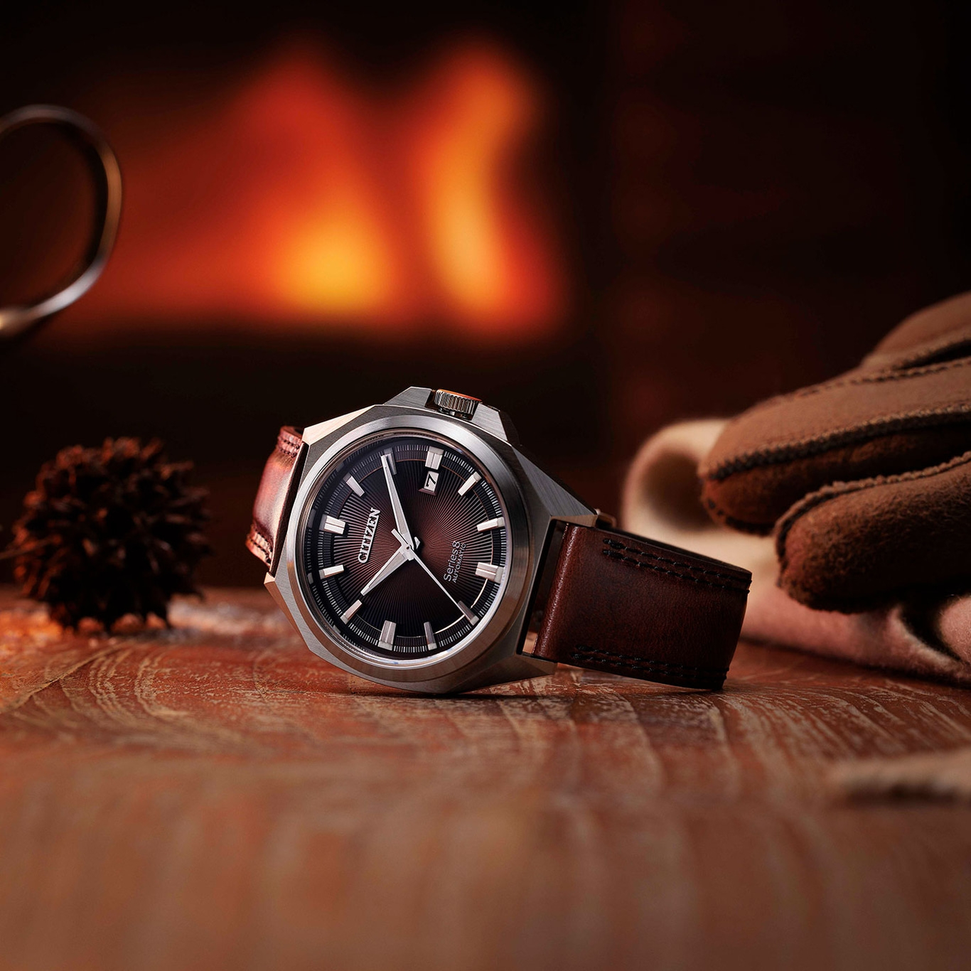 Citizen-Uhr auf Holzoberfläche mit Handschuhen und verschwommenem Hintergrund eines Kamins.