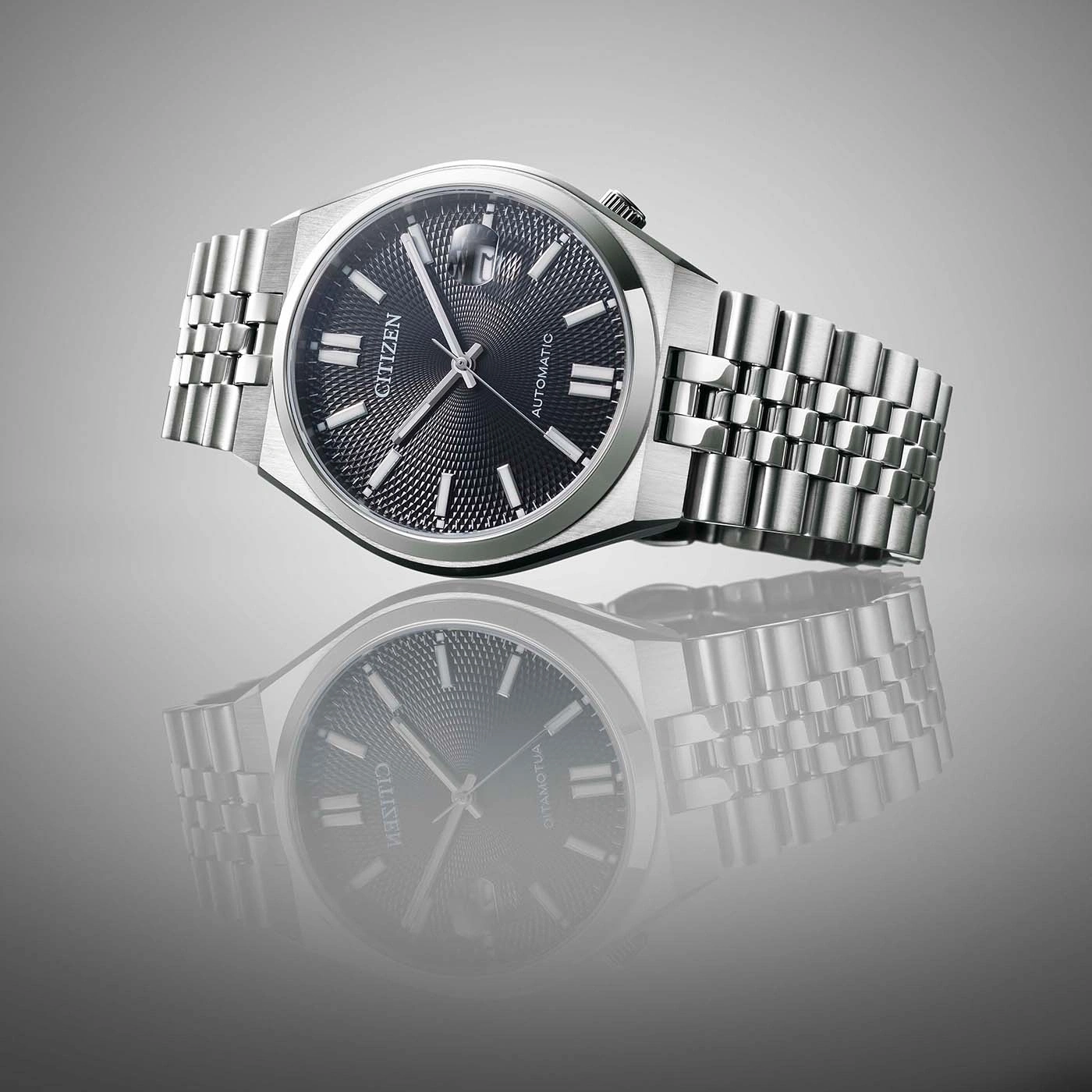 Montre Citizen automatique argentée sur fond gris avec reflet.