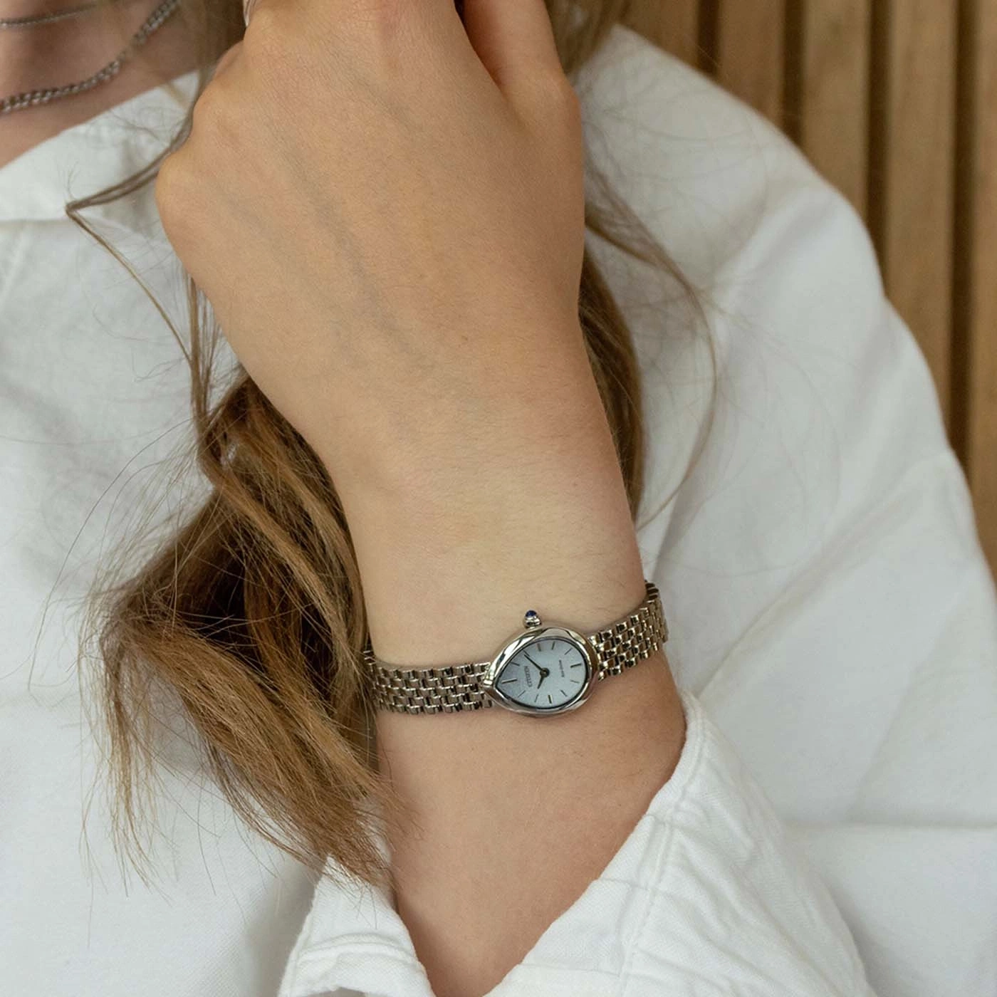 Eine filigrane Armbanduhr mit grauem, ovalem Zifferblatt am Handgelenk