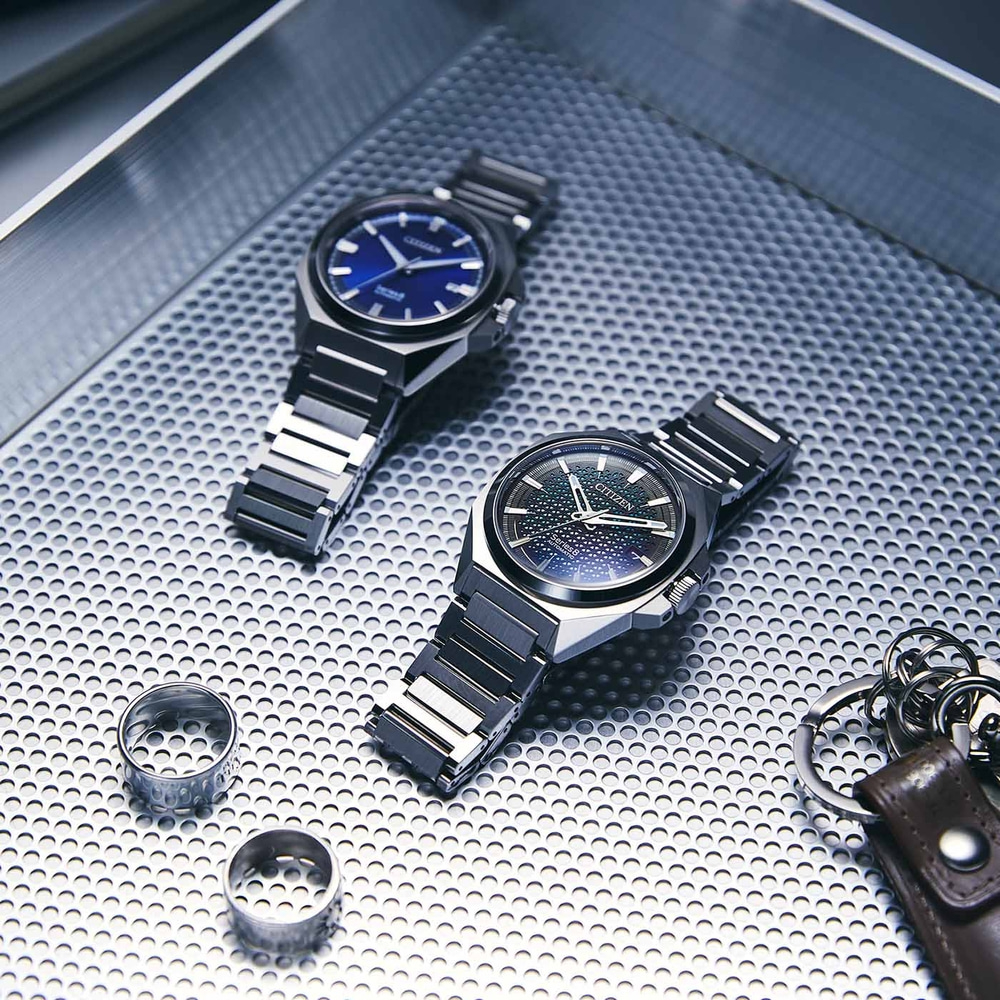 Deux montres, des bagues et un porte-clés sur une surface texturée.