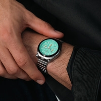 Le poignet d'un homme affiche une montre chronographe Citizen vert menthe avec un bracelet en acier inoxydable.