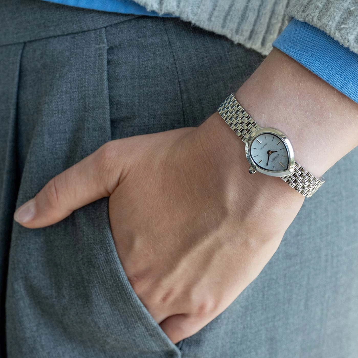 Eine Person mit einer silbernen Armbanduhr an einer grauen Hose