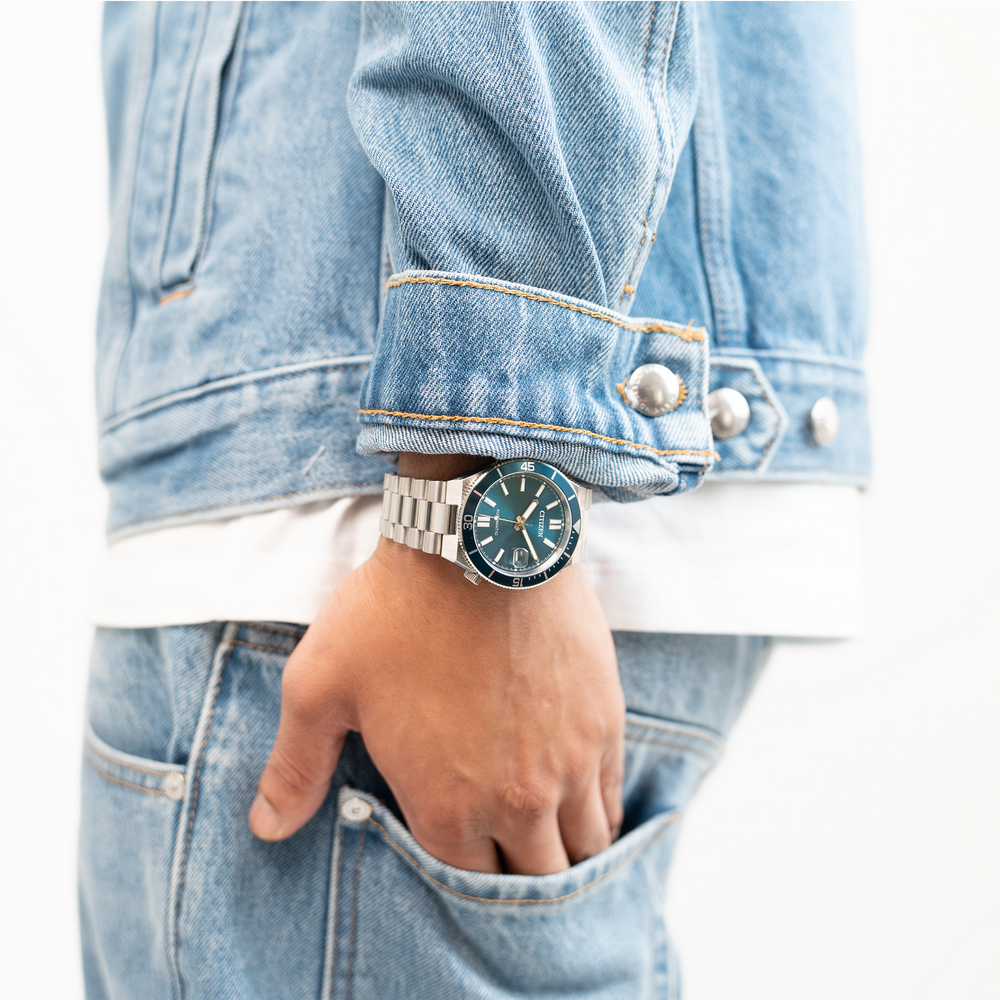 Mann trägt Jeansjacke und Jeans mit Uhr.