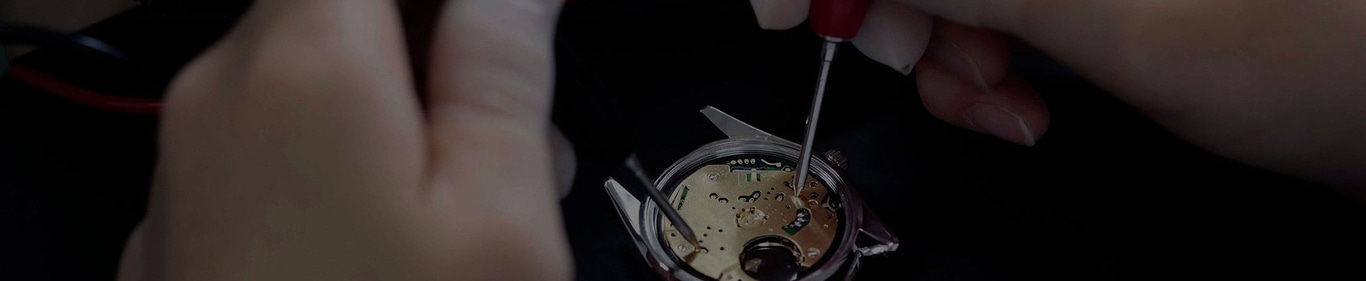 Uhrenreparatur mit Händen und Werkzeugen, Nahaufnahme des Uhrenmechanismus.