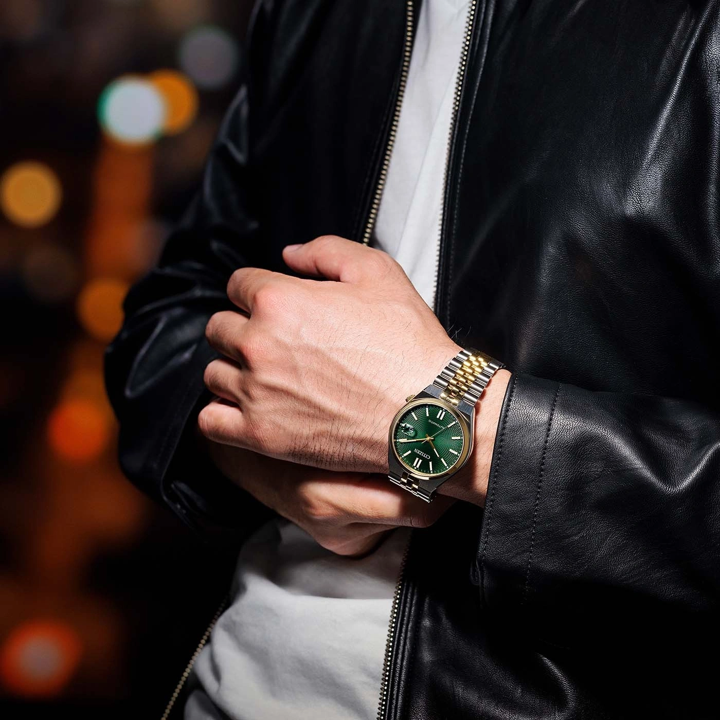 Homme portant une veste en cuir noire avec une montre verte au poignet.