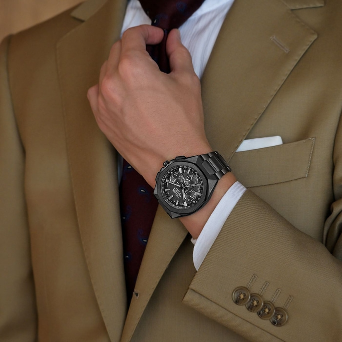 Mann im Anzug, der seine Krawatte richtet, mit schwarzer Uhr, Nahaufnahme.