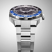 Gros plan d'une montre argentée avec une lunette bleue et noire et un bracelet en métal.