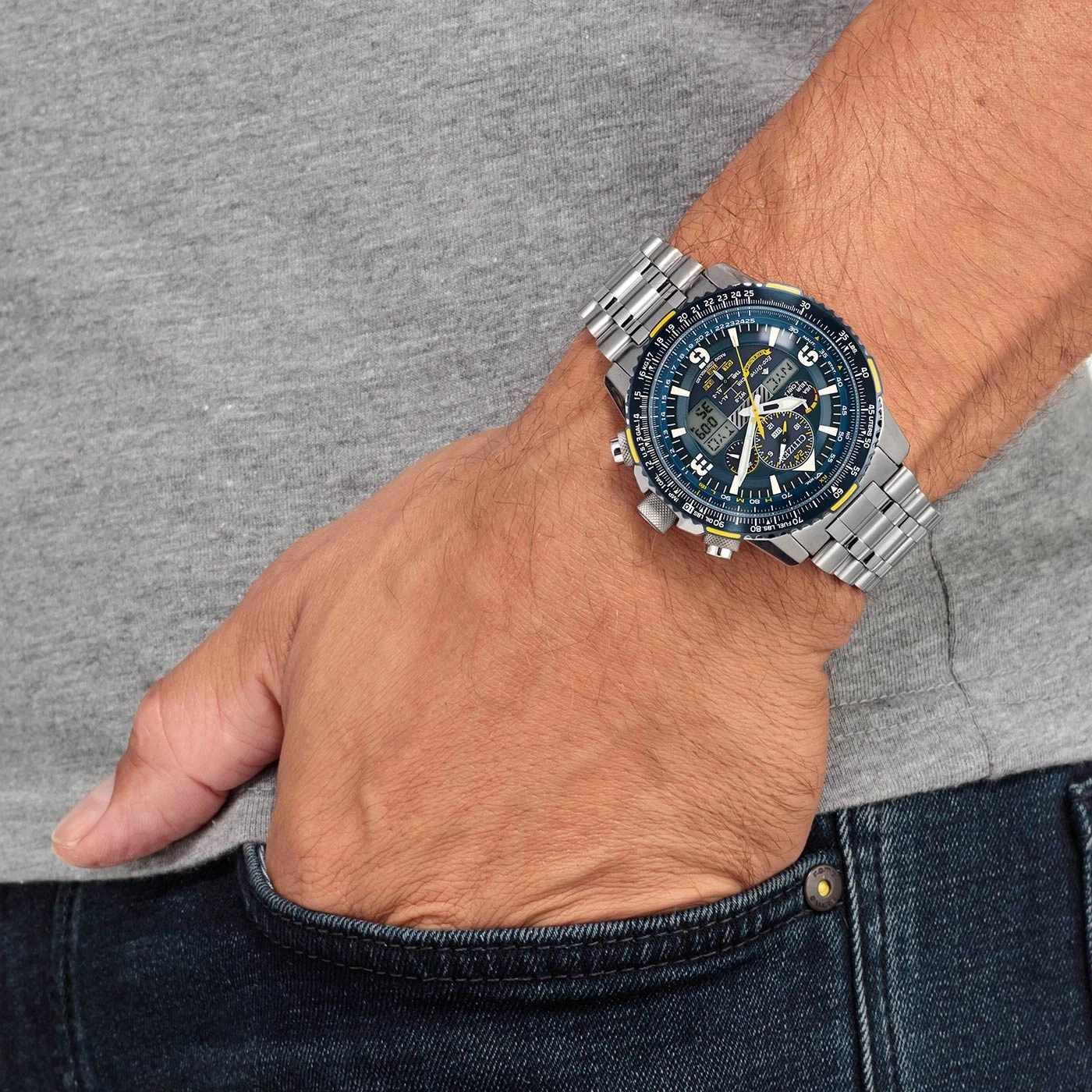 Eine silberne Herrenuhr mit blauem Zifferblatt wird am Handgelenk getragen.