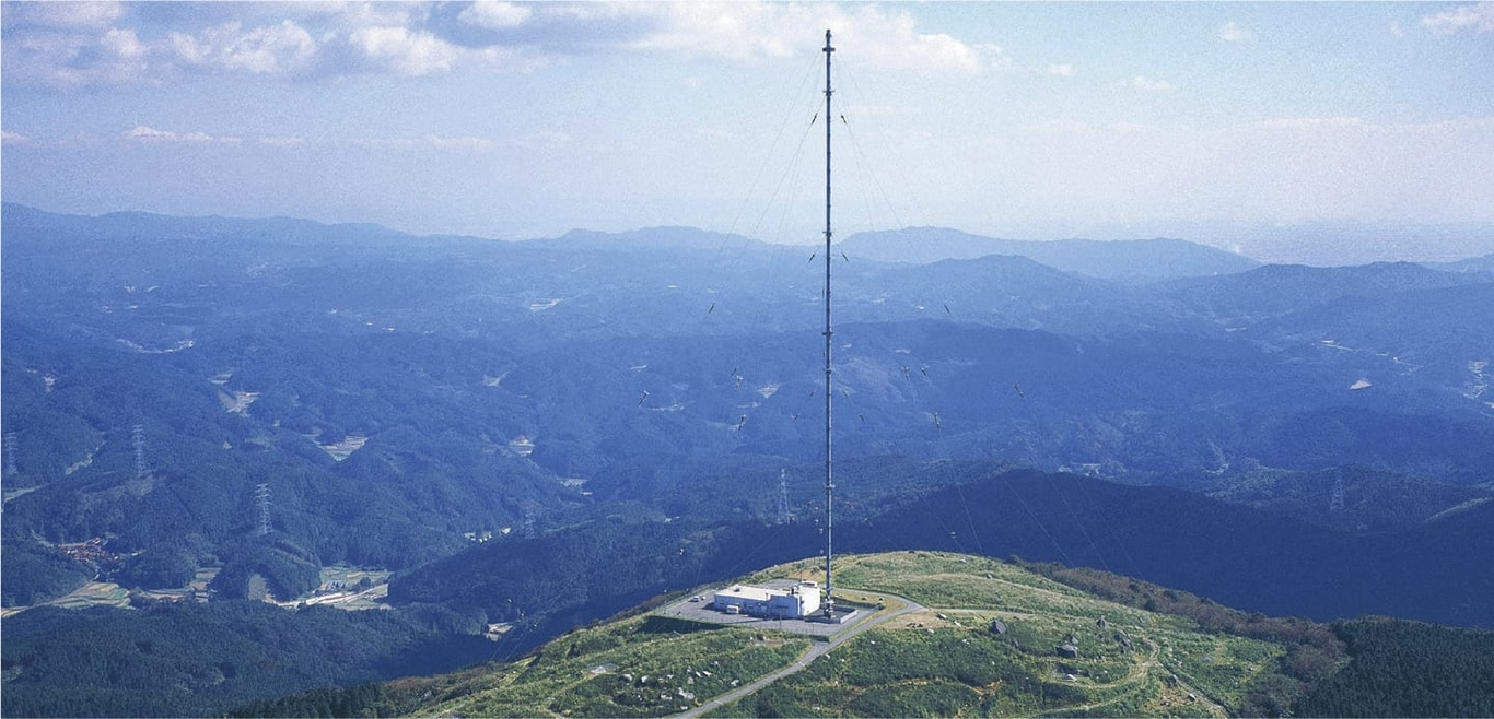 Ein hoher Radioturm auf einem Berg mit einer wunderschönen Landschaft.