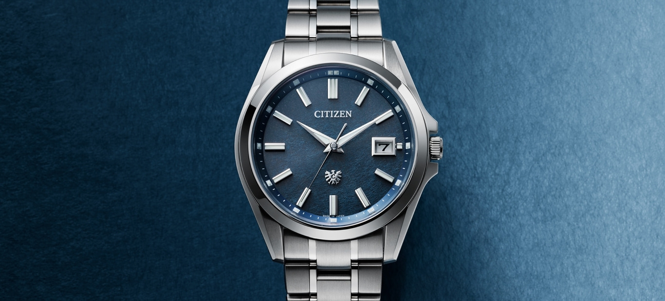 Citizen-Uhr mit blauem Zifferblatt und silbernem Armband auf blauem Hintergrund.