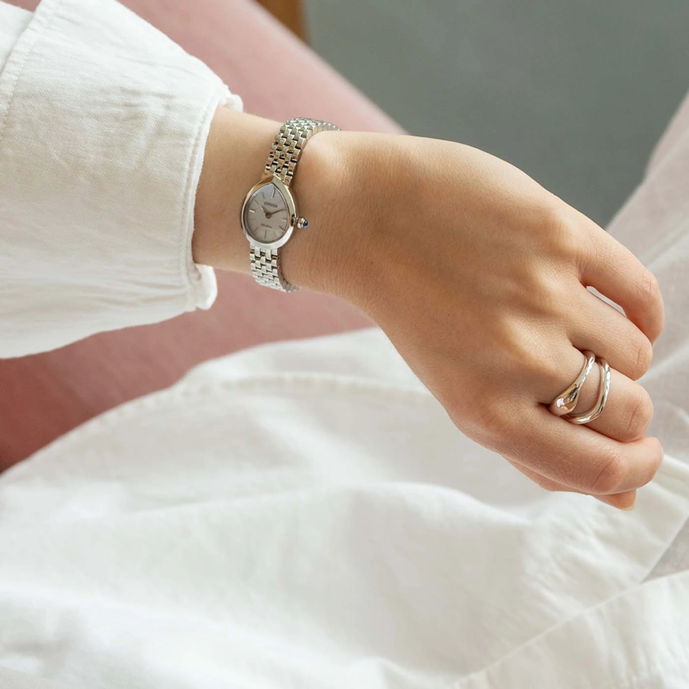 Eine Frau trägt eine elegante silberne Uhr und zarte Ringe.