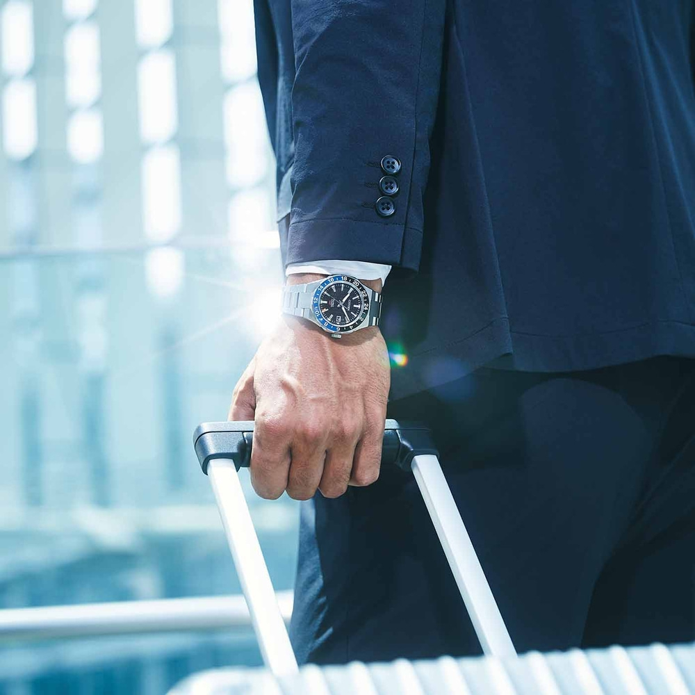 Homme en costume avec montre tenant des bagages, concept de voyage d'affaires.