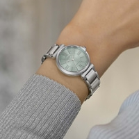 Le poignet d'une femme portant une montre argentée avec un cadran vert clair.