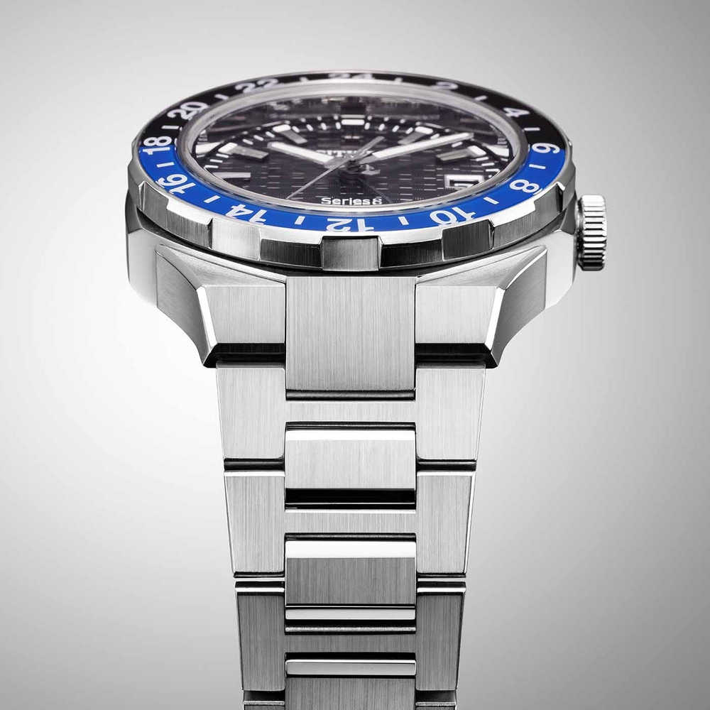 Gros plan d'une montre argentée avec une lunette bleue et noire et un bracelet en métal.