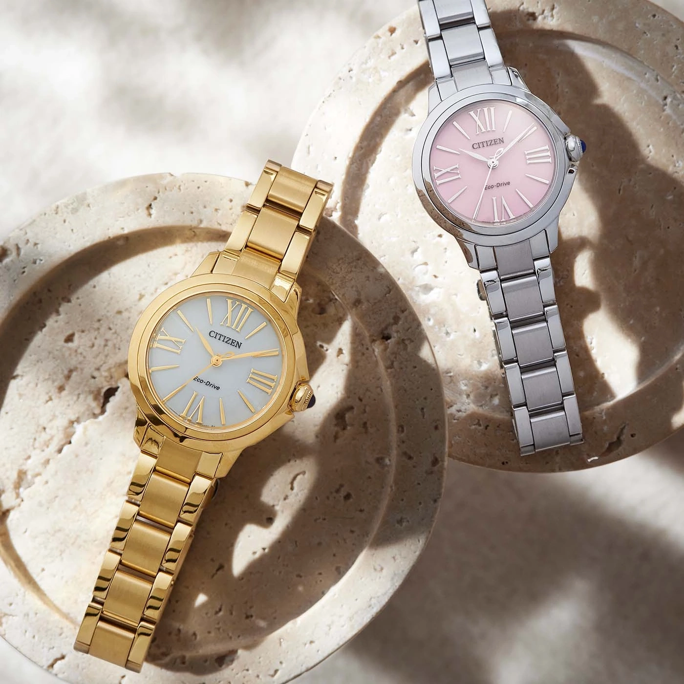 Deux montres Citizen, une dorée et une argentée avec cadran rose.