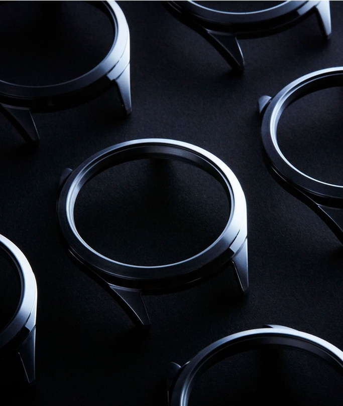 Uhrgehäuse auf dunkler Oberfläche angeordnet, metallisch und glänzend.