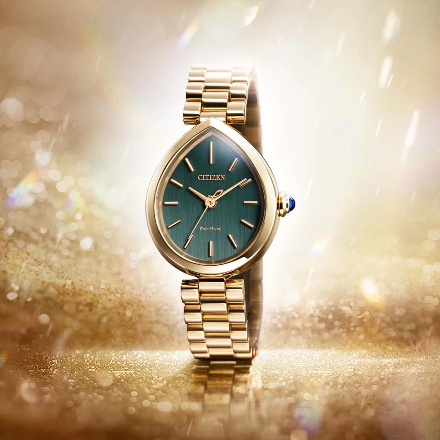 Eine goldene Citizen Eco-Drive-Uhr mit grünem Zifferblatt auf einem funkelnden Hintergrund.